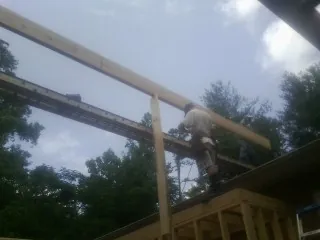 Carpenter setting a ridge beam over a new addition frame — Ice Dam Removal by Roofing Brothers in Earlsboro