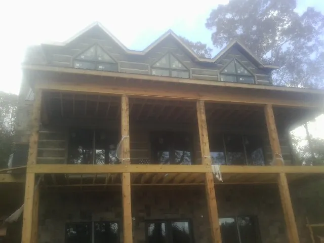 Dormers and porch framing on a large log home under construction — Roof Coating work by our crew in Earlsboro