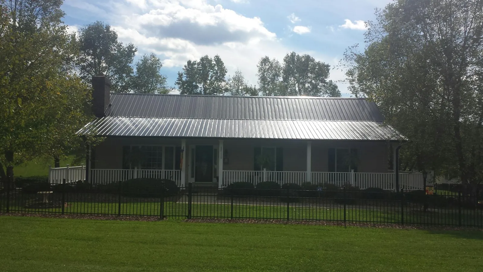 Gray metal roof on a brick ranch with a full width front porch — Gutter Guard Installation work by our crew in Earlsboro