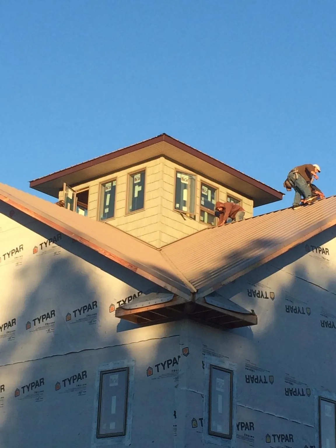 Roofers working around a rooftop cupola on a new metal roof at sunset — Roof Waterproofing in Earlsboro by Roofing Brothers